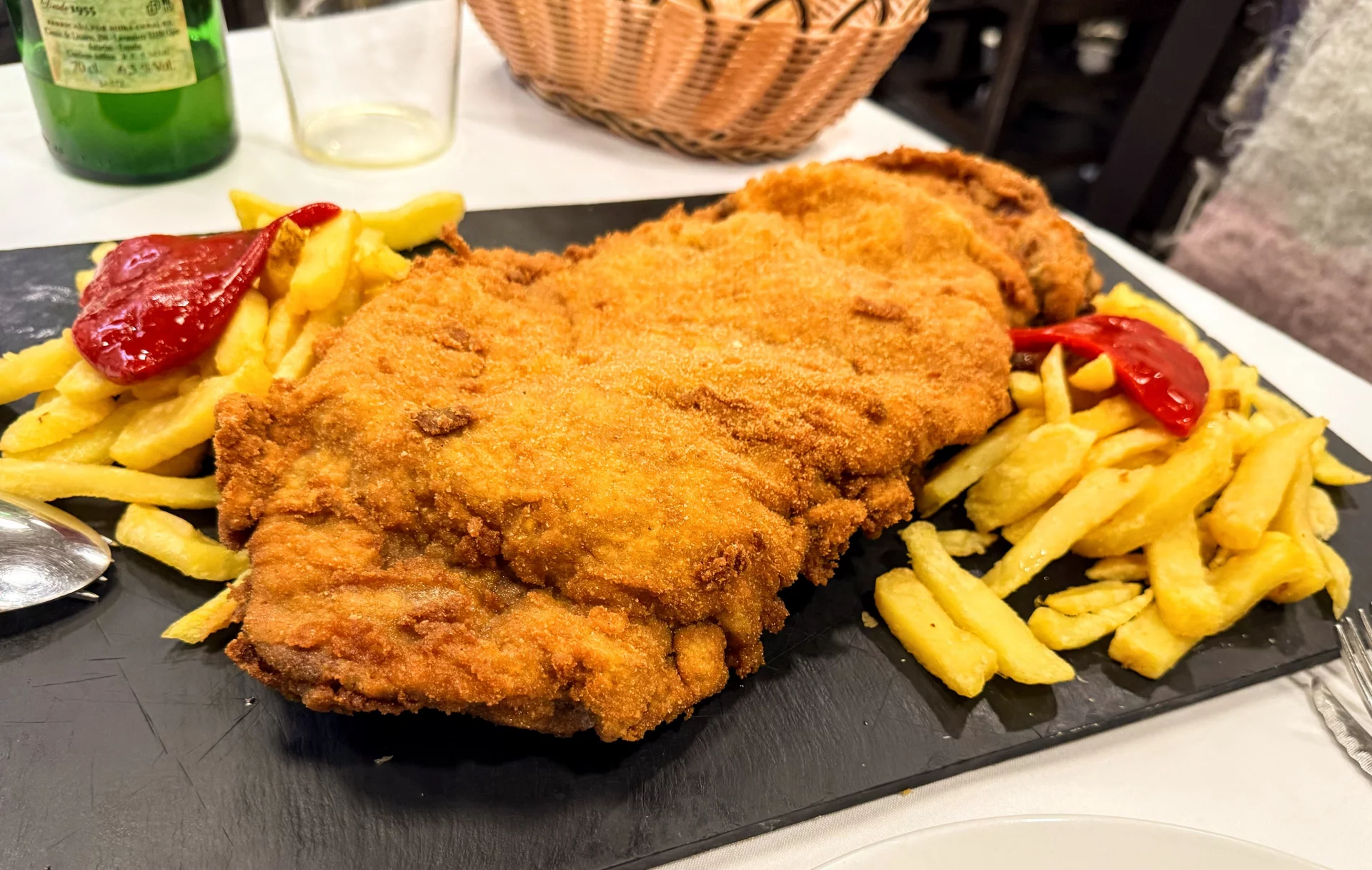 Cachopo tradicional asturiano servido en pizarra con patatas fritas y pimientos